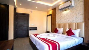 Ein Hotelzimmer mit einem Bett, einer Holztür, einer Wandklimaanlage und einer rot-weißen Bettdecke.