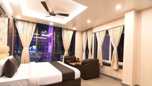 Une chambre d’hôtel moderne avec un grand lit, un canapé, une petite table et un ventilateur de plafond.