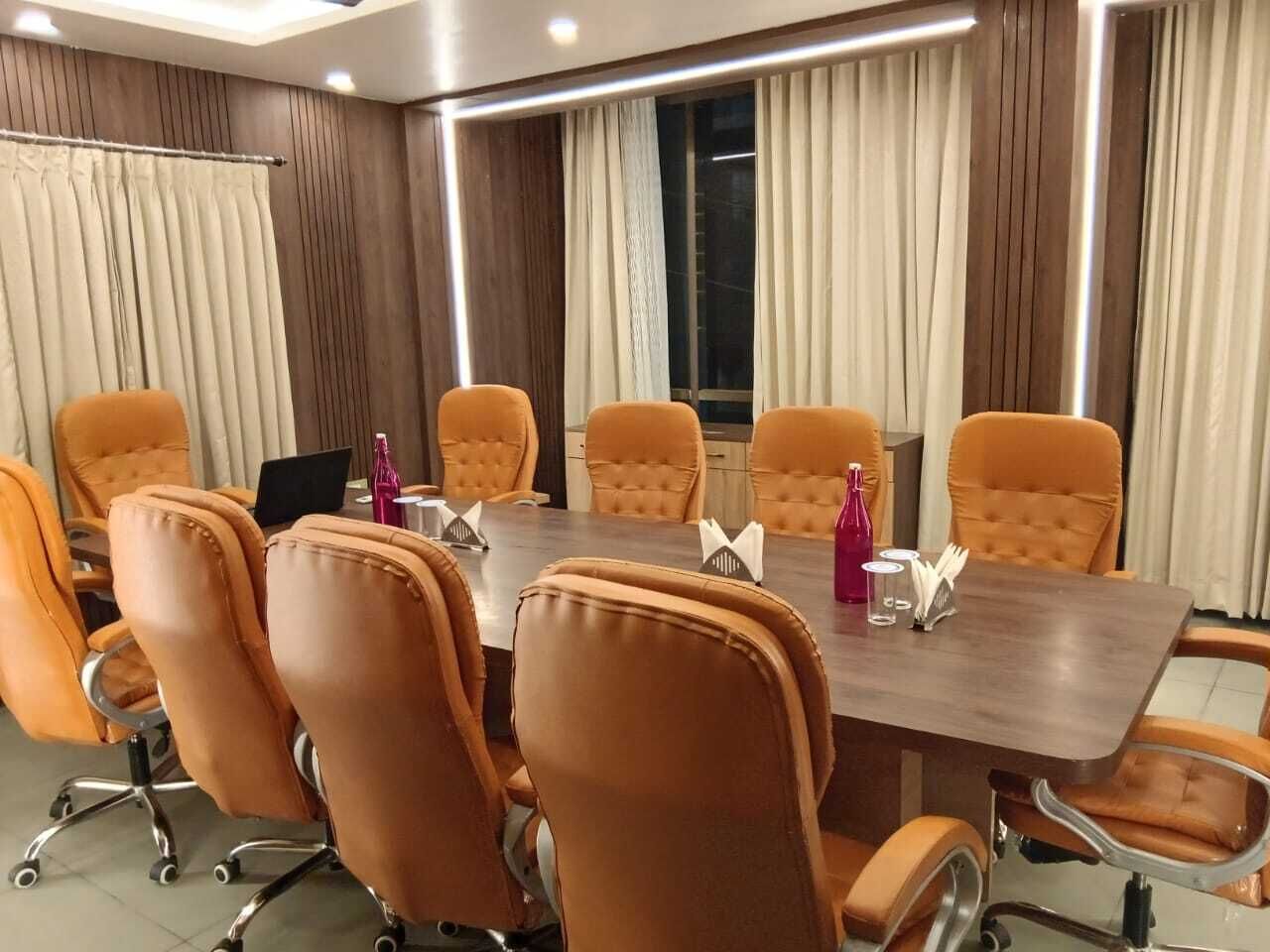 Una sala de conferències amb una taula llarga i vuit cadires taronges.