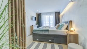 A modern bedroom with a bed, bedside tables, a TV, and a window with curtains. - Wellness Escape Villa One (Novi Vinodolski)