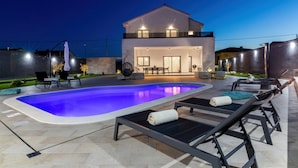 A modern house with a swimming pool, outdoor seating, and a well-lit patio area. - Wellness Escape Villa One (Novi Vinodolski)