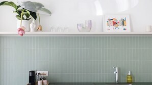 A kitchen with a round wooden table, a bowl of lemons, a coffee maker, and a sink.