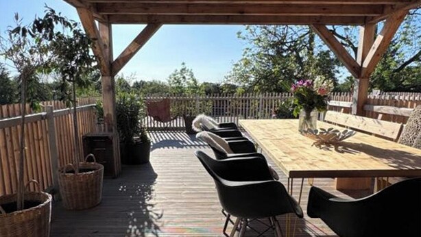 An outdoor wooden deck with a table and chairs, surrounded by a wooden fence and trees. - SunDeck Apartment (Am Ettersberg)