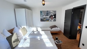A modern bedroom with a large bed, a smaller bed, a wardrobe, and a painting on the wall. - SunDeck Apartment (Am Ettersberg)