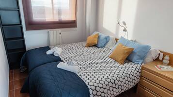 Un llit ben arropat amb un estovat estampat, dues almoines i tovalloles esteses.