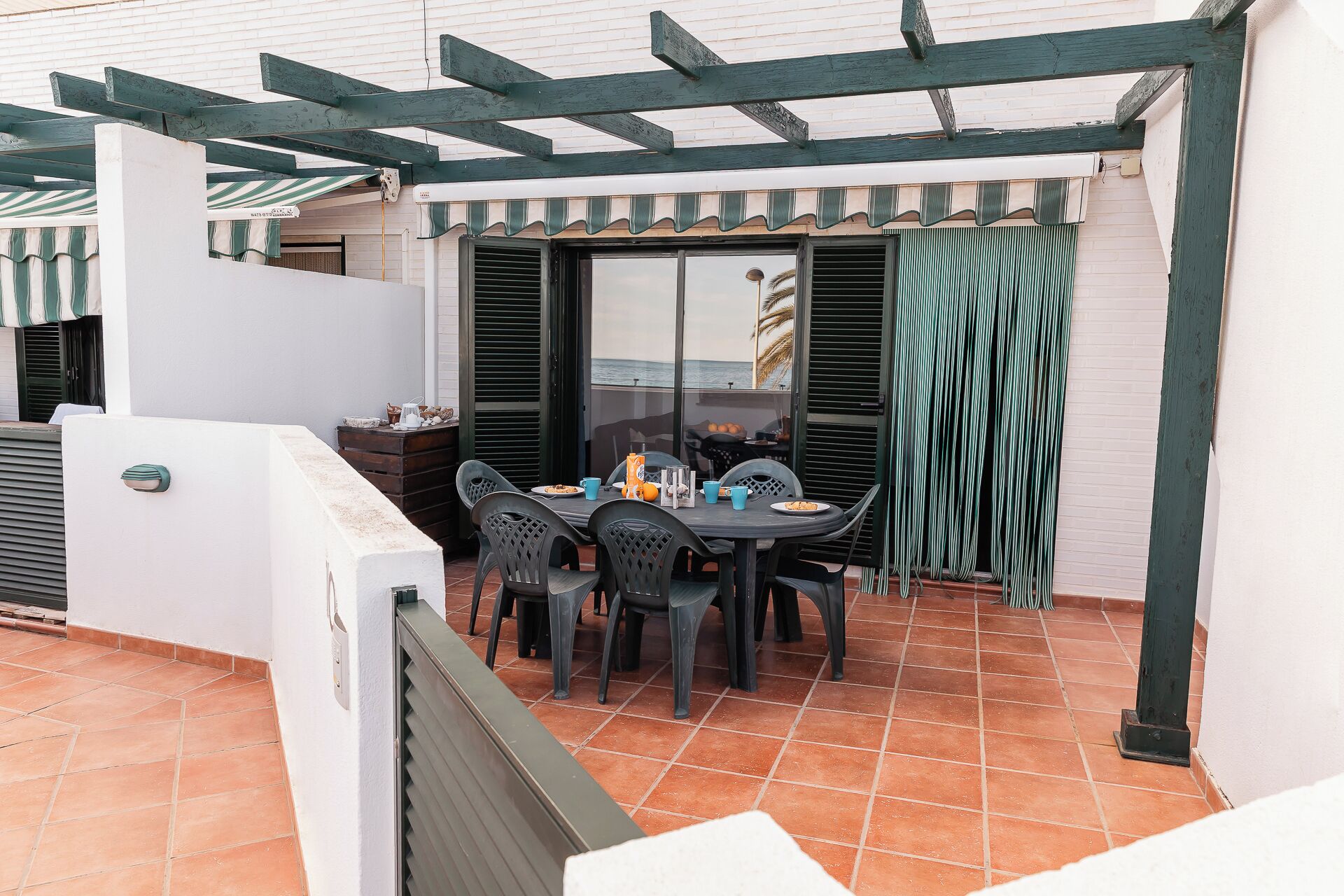Un patio con mesa y sillas, una parrilla y vista al mar.