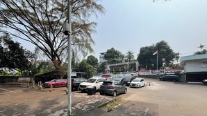 Een parkeerplaats met meerdere auto's, een vlag en een gebouw op de achtergrond.