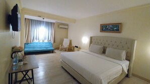 Een hotelkamer met een groot bed, een blauwe bank, een houten tafel en een stoel.