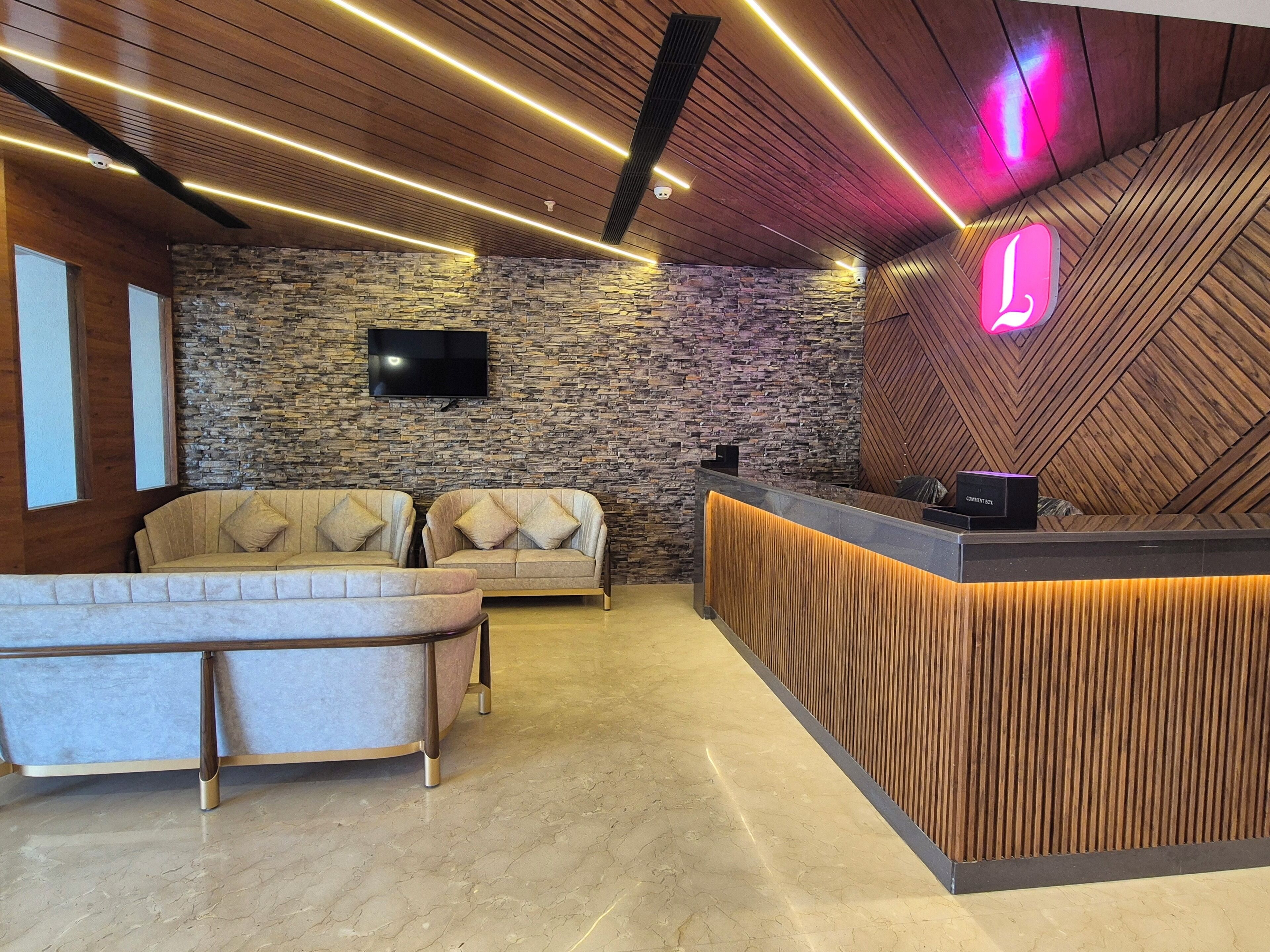 A modern reception area with a stone wall, two sofas, a wooden reception desk, and a neon sign.