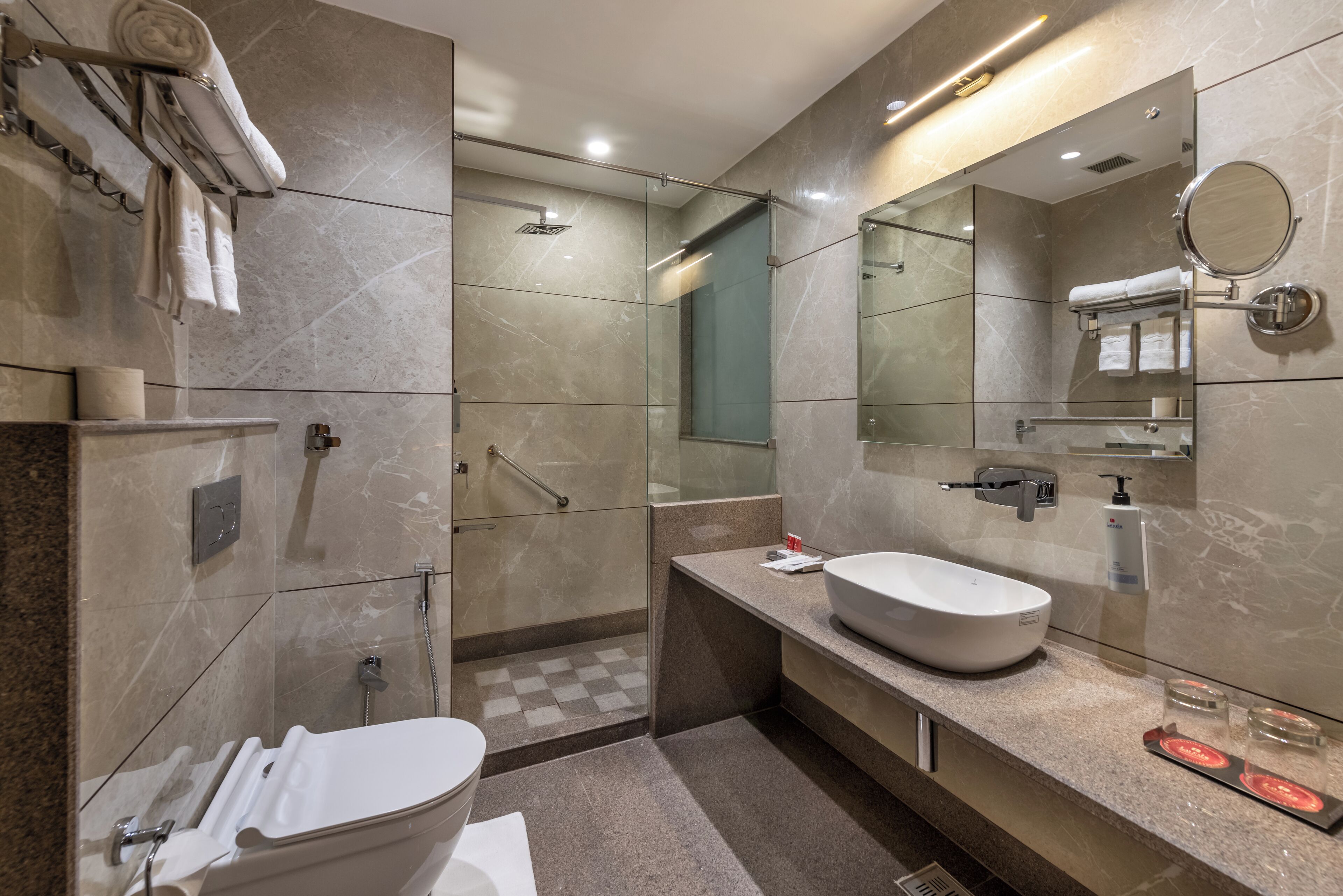 A modern bathroom with a large mirror, a white sink, and a shower area.