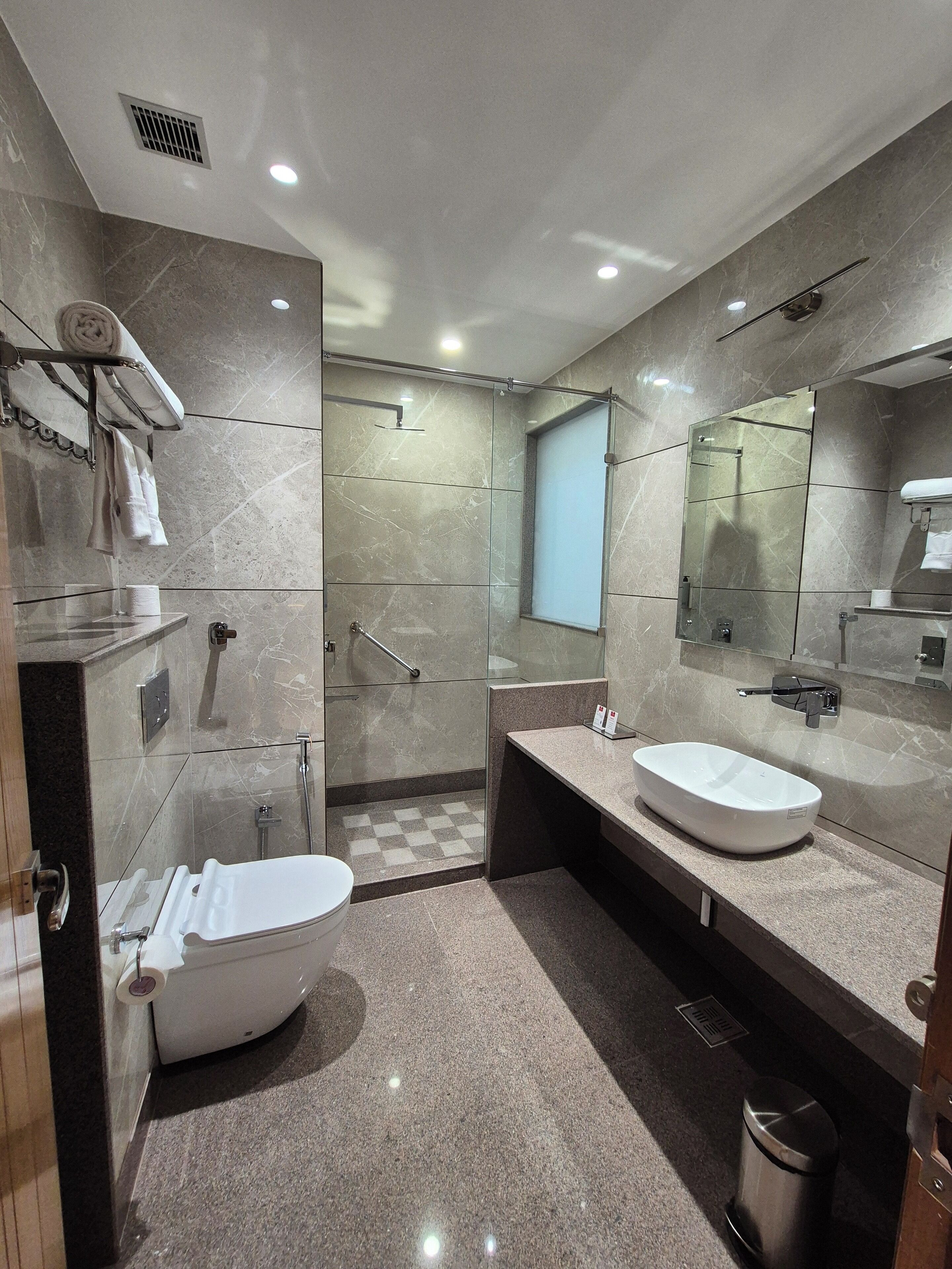 A modern bathroom with a freestanding bathtub, two sinks, a glass shower enclosure, and a large mirror.