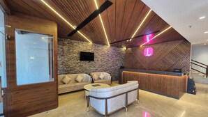 Un'area reception moderna con parete in pietra, soffitto in legno e scrivania.