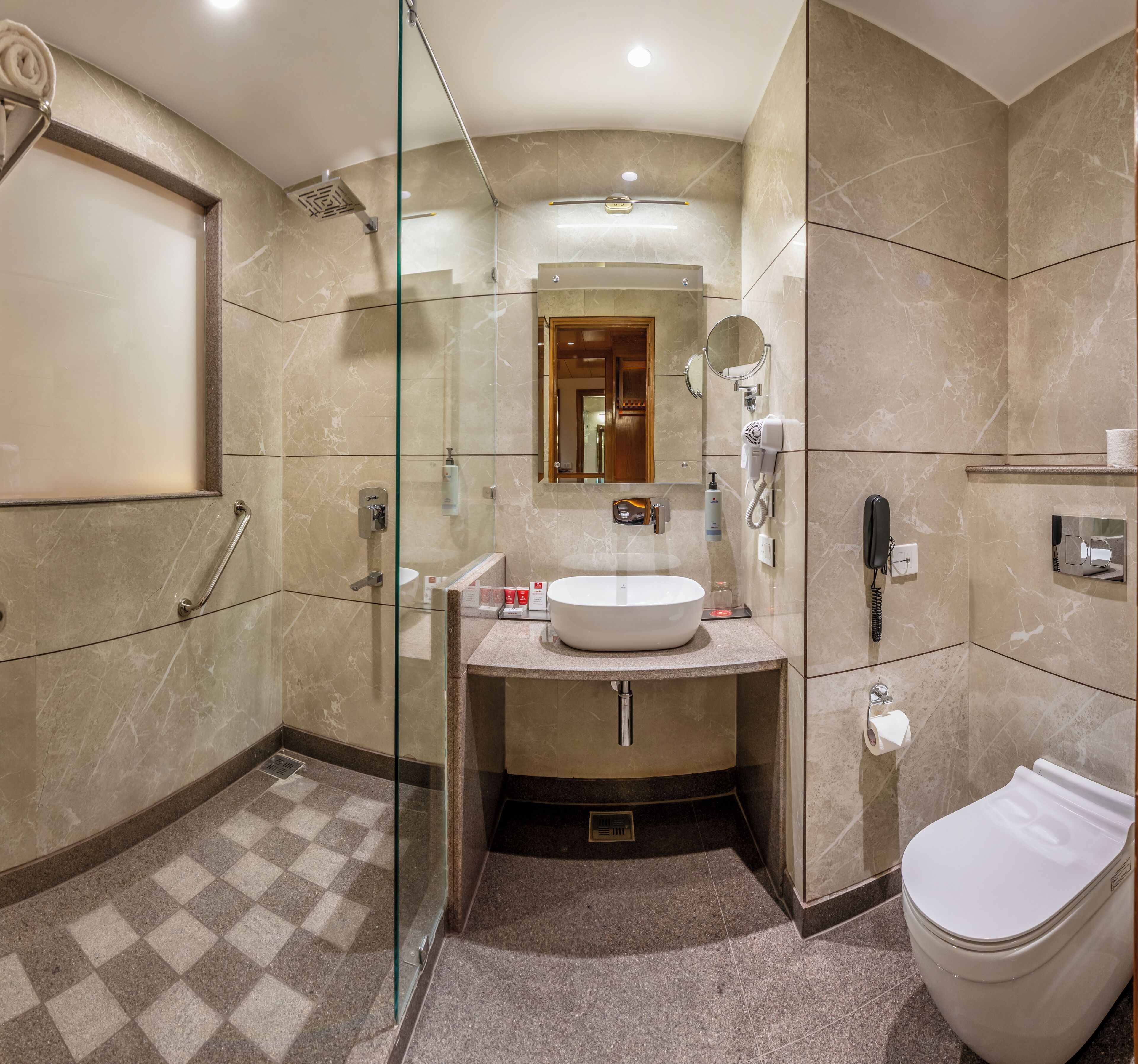 Un baño moderno con ducha de vidrio, un lavamanos redondo y un inodoro.