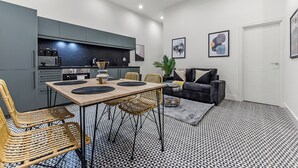 A modern kitchen with grey cabinets, a dining table with chairs, and a black and white patterned floor. - Convenient 2BR 2BA / near Tube Station (London)