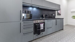 A modern kitchen with grey cabinets, a black countertop, and a patterned floor. - Convenient 2BR 2BA / near Tube Station (London)