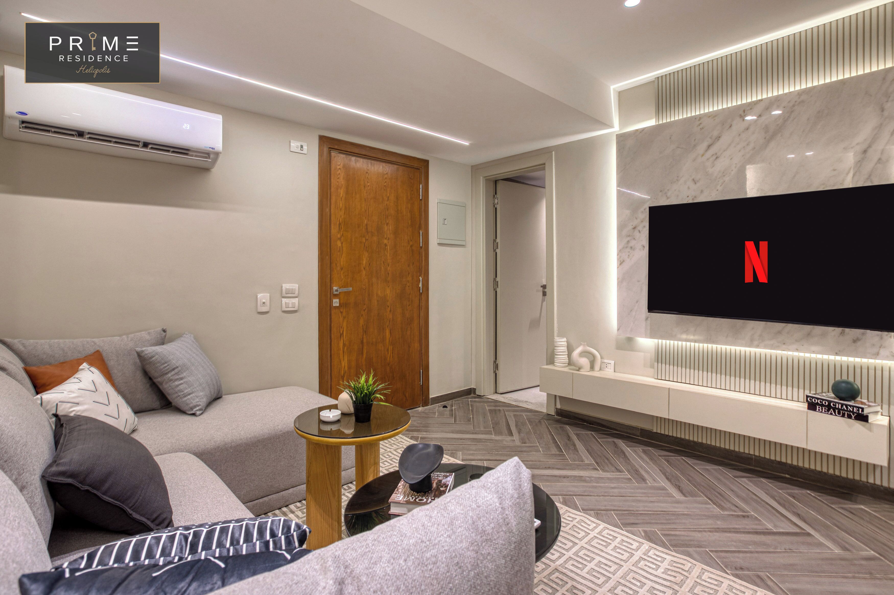 A modern living room with a sofa, coffee table, and a flat-screen TV mounted on the wall.