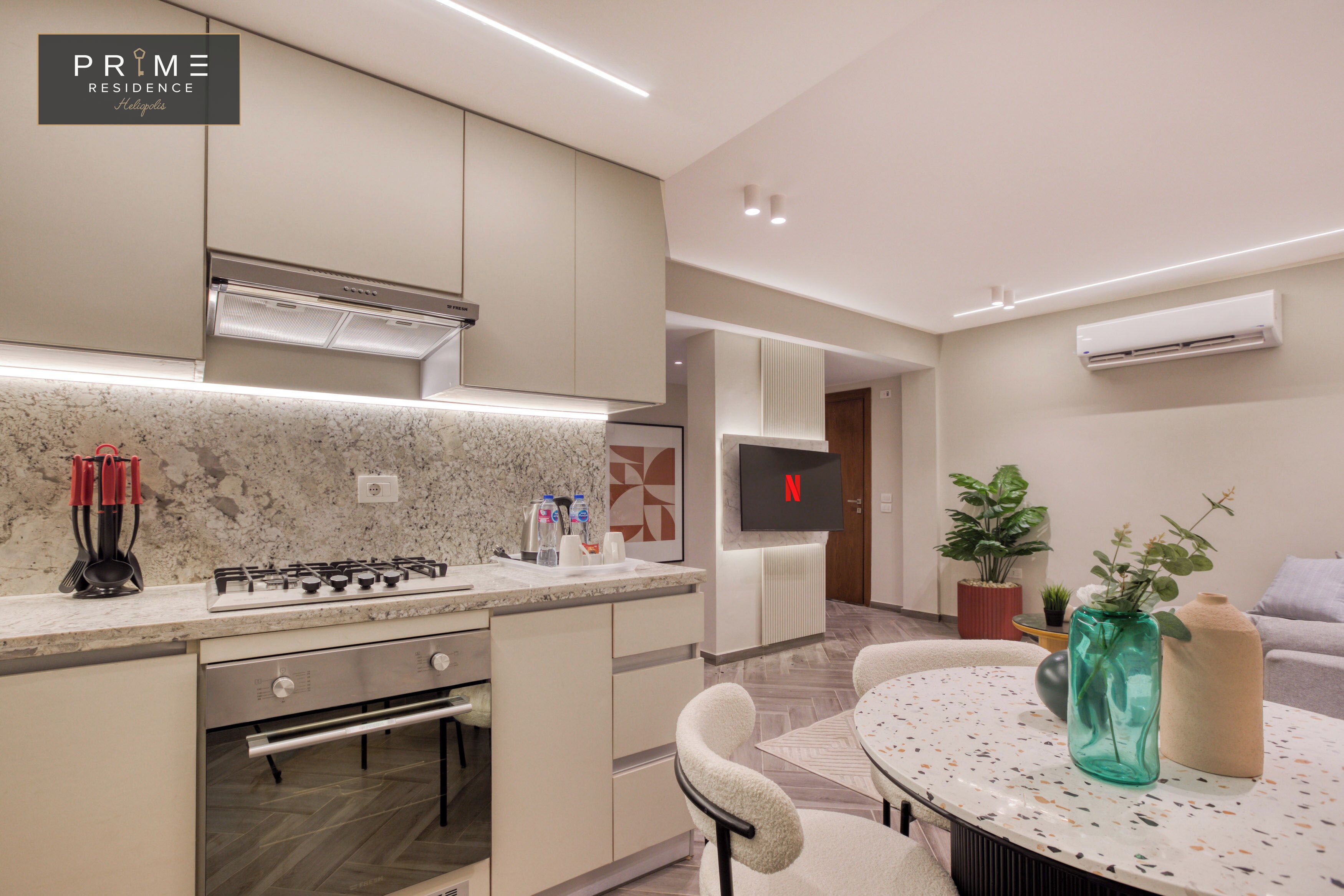 A modern kitchen with a built-in stove, oven, and microwave. There is a dining area with a round table and chairs.