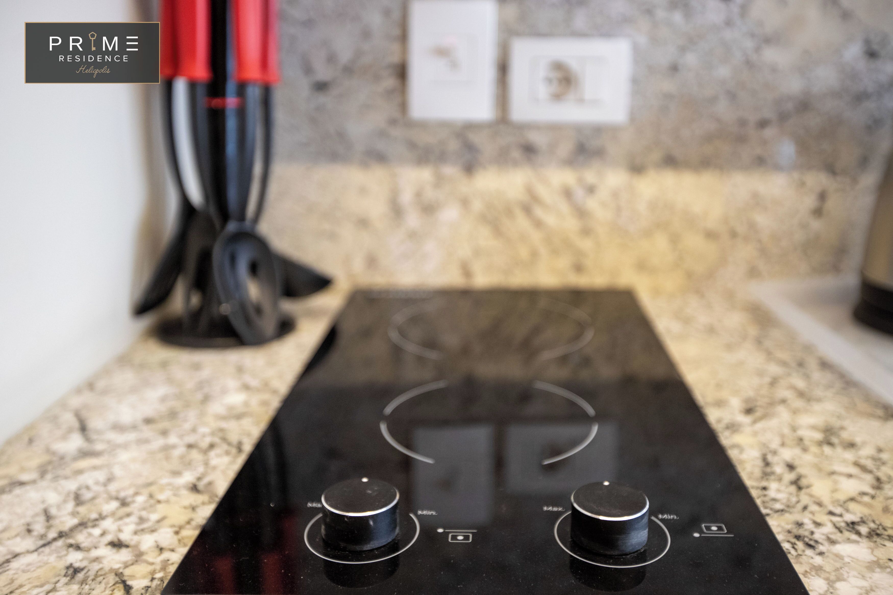 A kitchen with a black induction cooktop and granite countertops.