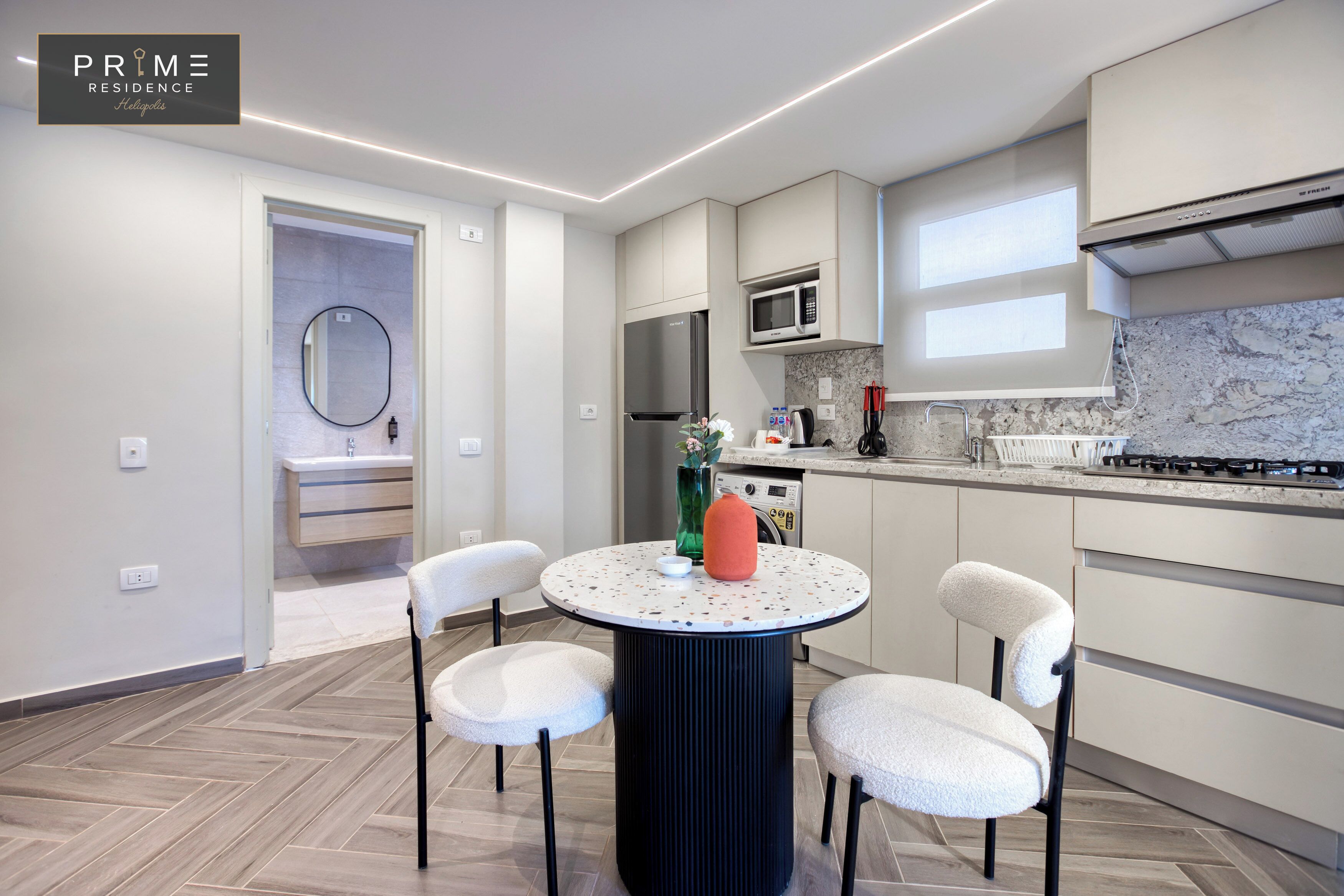 A modern kitchen with a round table, chairs, a microwave, and a gas stove.