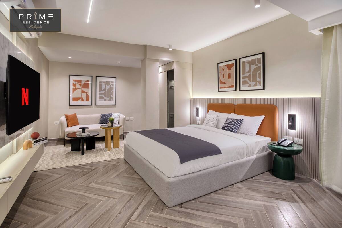 Una habitación de hotel moderna con una cama grande, un sofá, un televisor y una pequeña mesa.