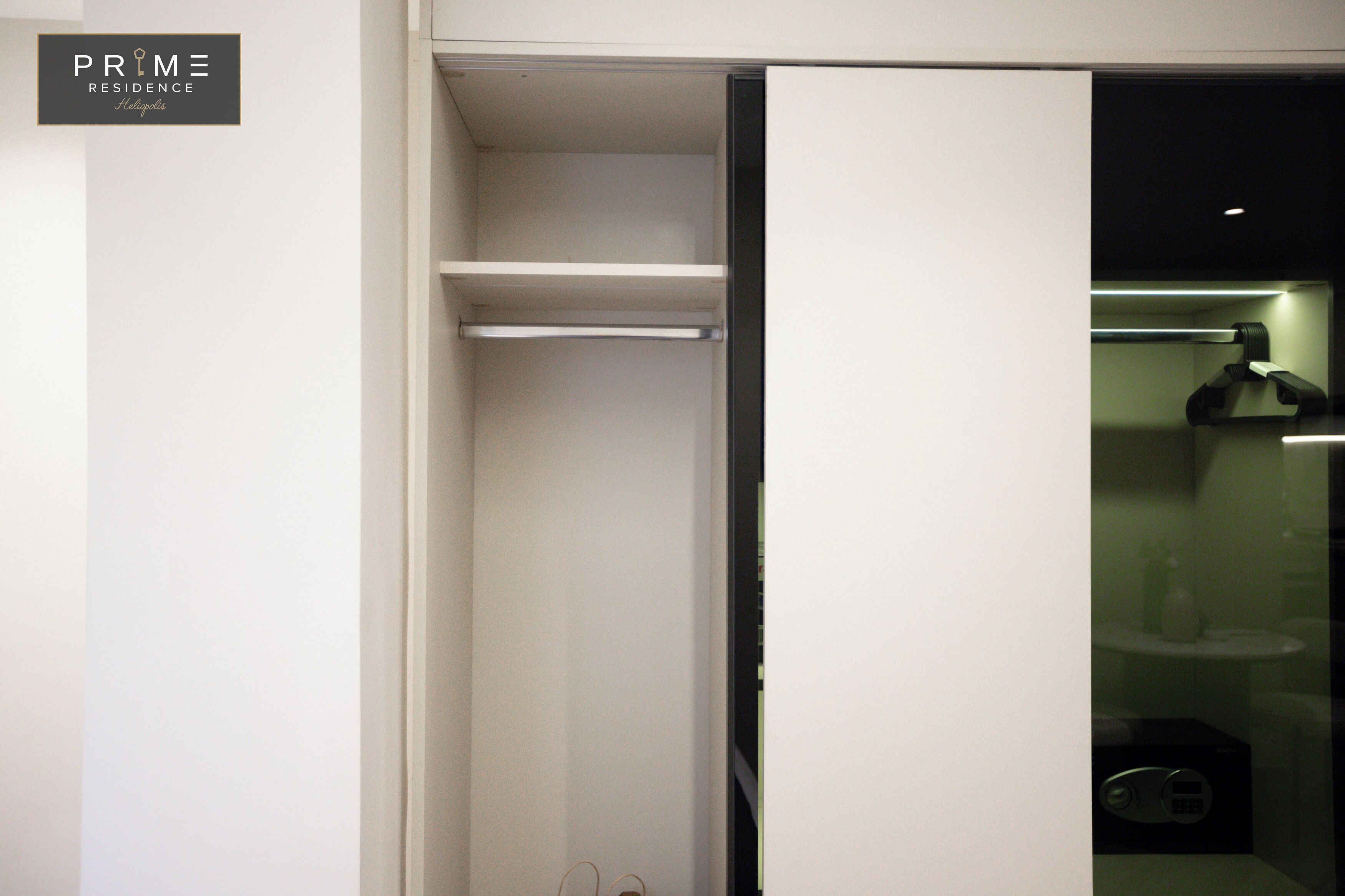 A hotel room with a closed closet, a visible bathroom with a sink and mirror, and a sign indicating the hotel name and location.