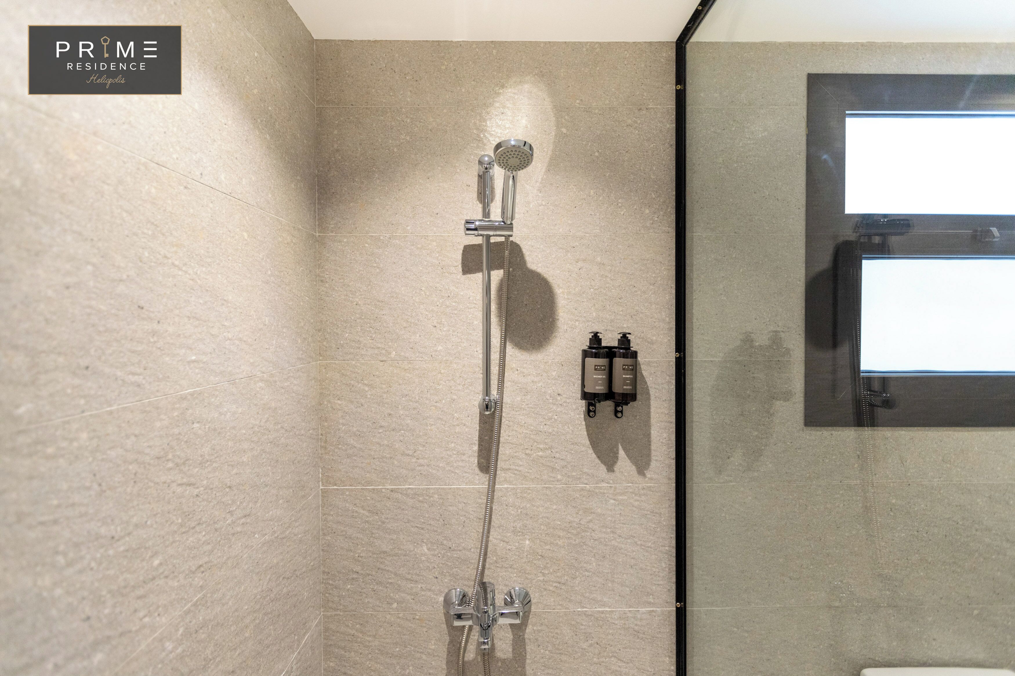 A shower with a handheld showerhead and a wall-mounted control panel.