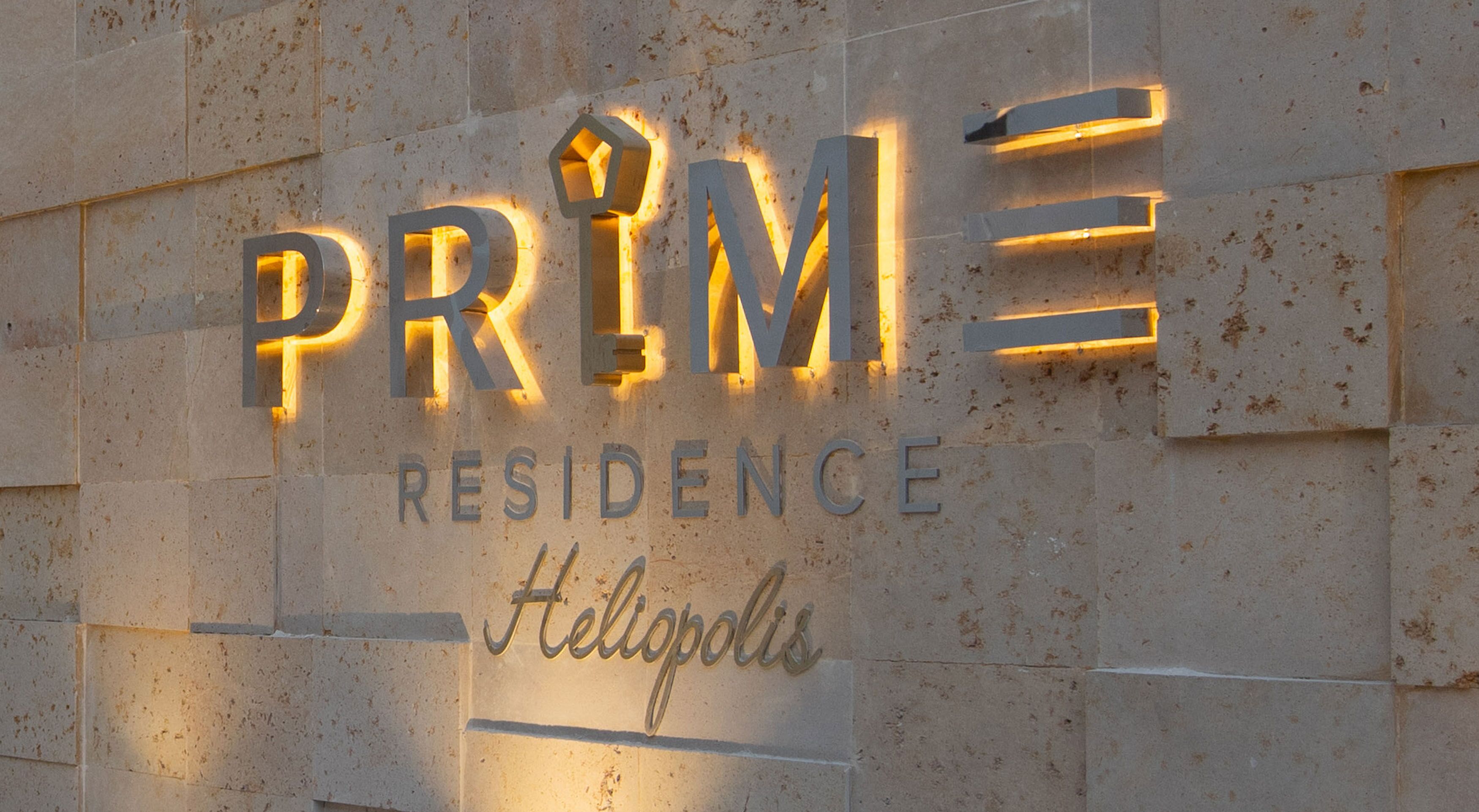 Un cartel que dice 'PRIME Residence' con letras iluminadas y la palabra 'Hellopolis' debajo.