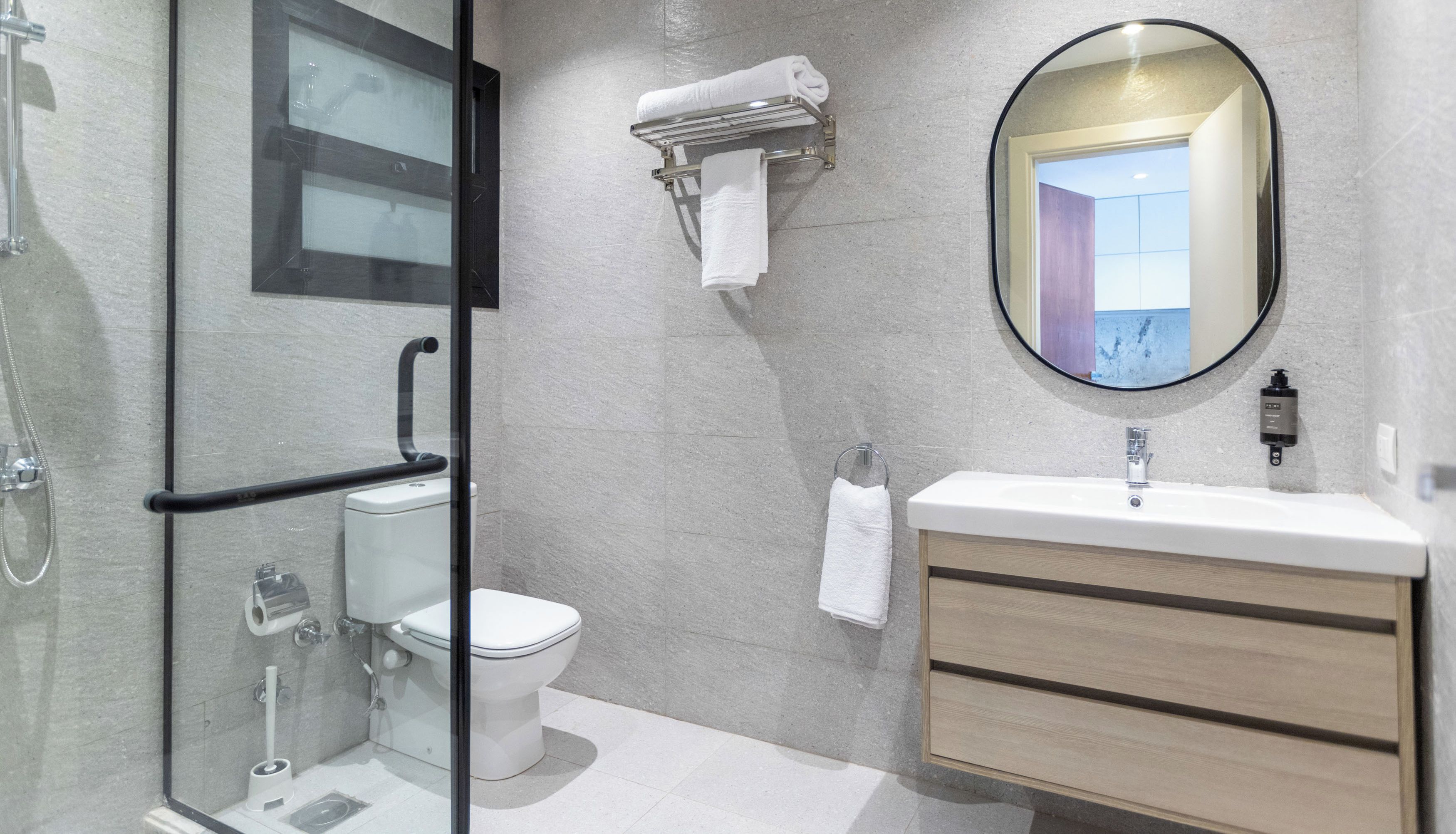 A modern bathroom with a glass-enclosed shower, a toilet, a vanity with a mirror, and a towel rack.