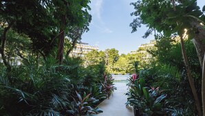 A pathway flanked by lush greenery leading to a building with multiple balconies. - Welcome to Mistiq Temple II in Tulum, where modern luxury meets the natural beauty of the region (Tulum)