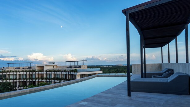 A rooftop pool with a covered seating area and a view of buildings in the background. - Welcome to Mistiq Temple II in Tulum, where modern luxury meets the natural beauty of the region (Tulum)