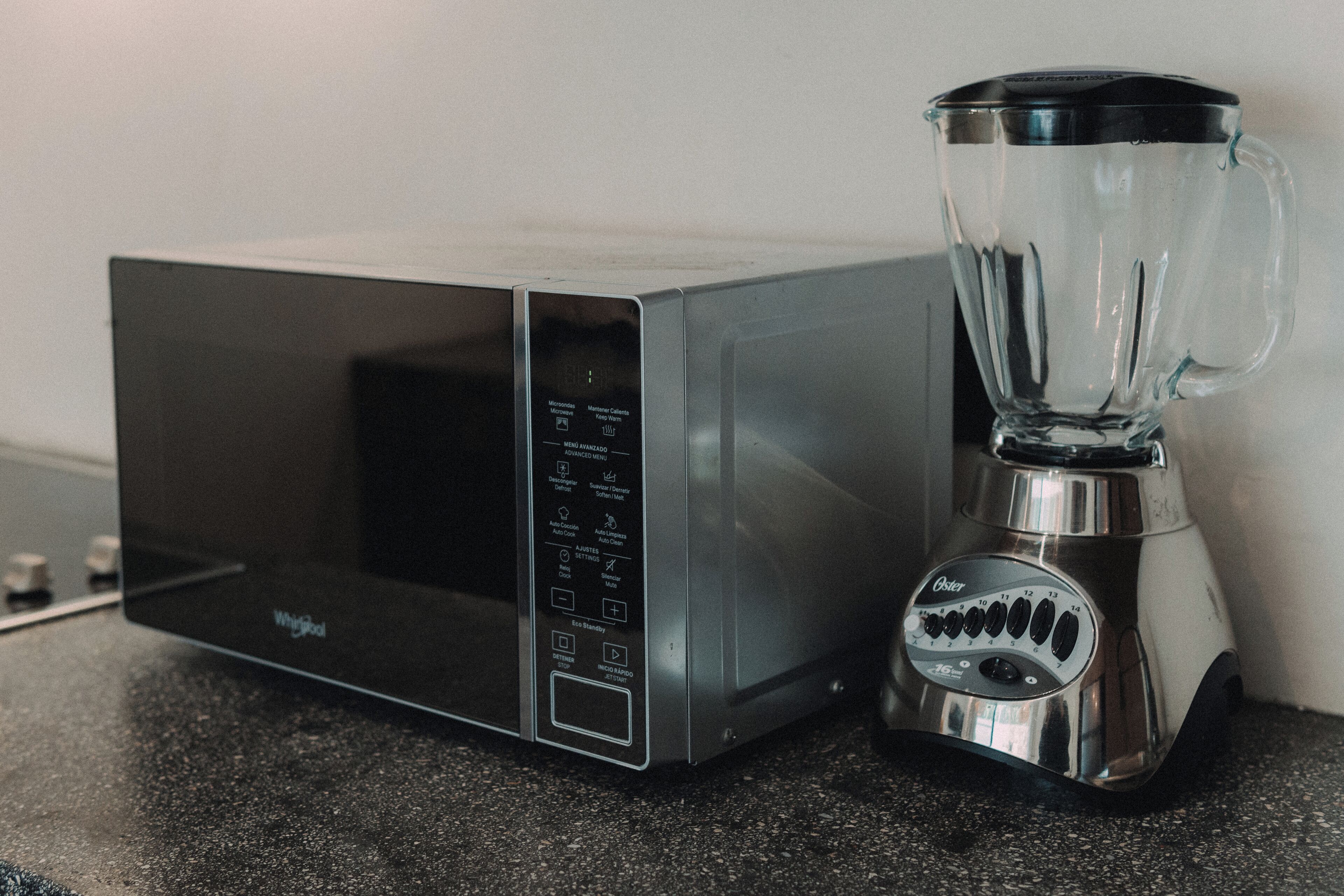 A kitchen with a microwave and a blender on a countertop.