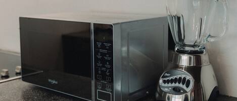 A kitchen with a microwave and a blender on a countertop.