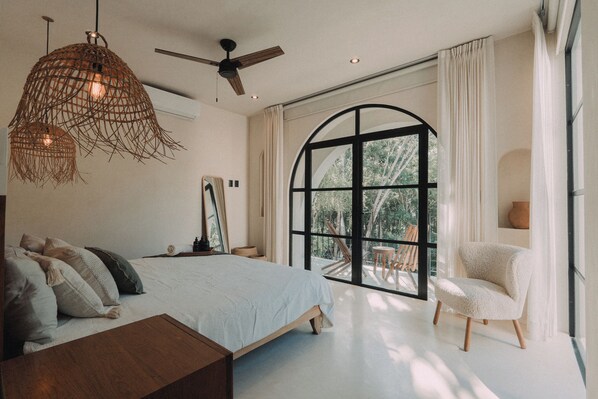 Une chambre avec une grande fenêtre, un lit, une chaise et un ventilateur de plafond.