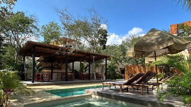 A pool area with a wooden pergola, lounge chairs, and a thatched-roof structure. - This villa is a 2 bedroom(s), 2.5 bathrooms, located in Tulum, Quintana Roo. (Tulum)