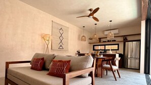A modern living room with a sofa, dining table, and chairs. There is a ceiling fan and pendant lights. - This villa is a 2 bedroom(s), 2.5 bathrooms, located in Tulum, Quintana Roo. (Tulum)
