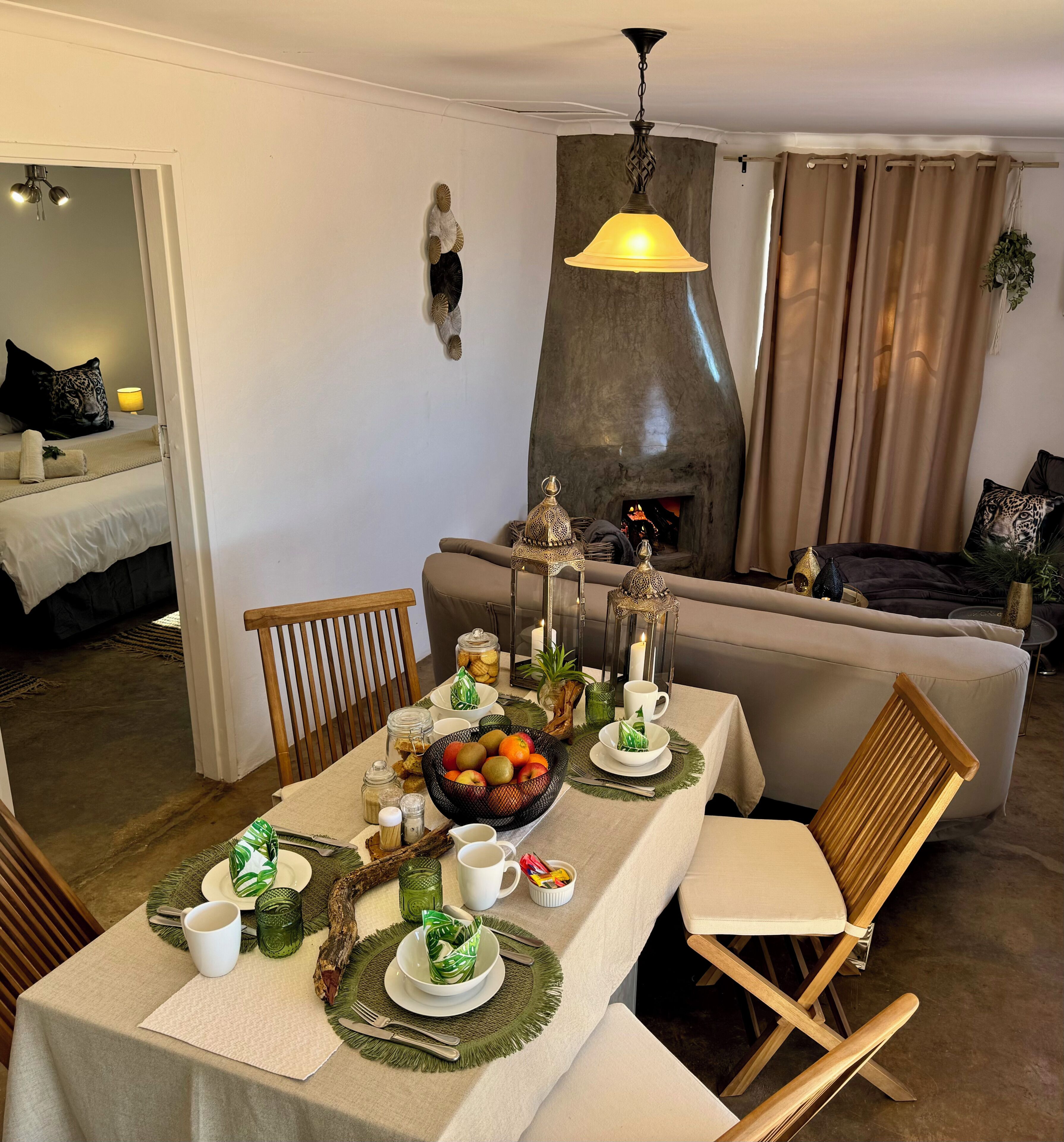 Ein Essbereich mit einem für zwei Personen gedecktem Tisch, einer Couch im Hintergrund und einem Kamin.