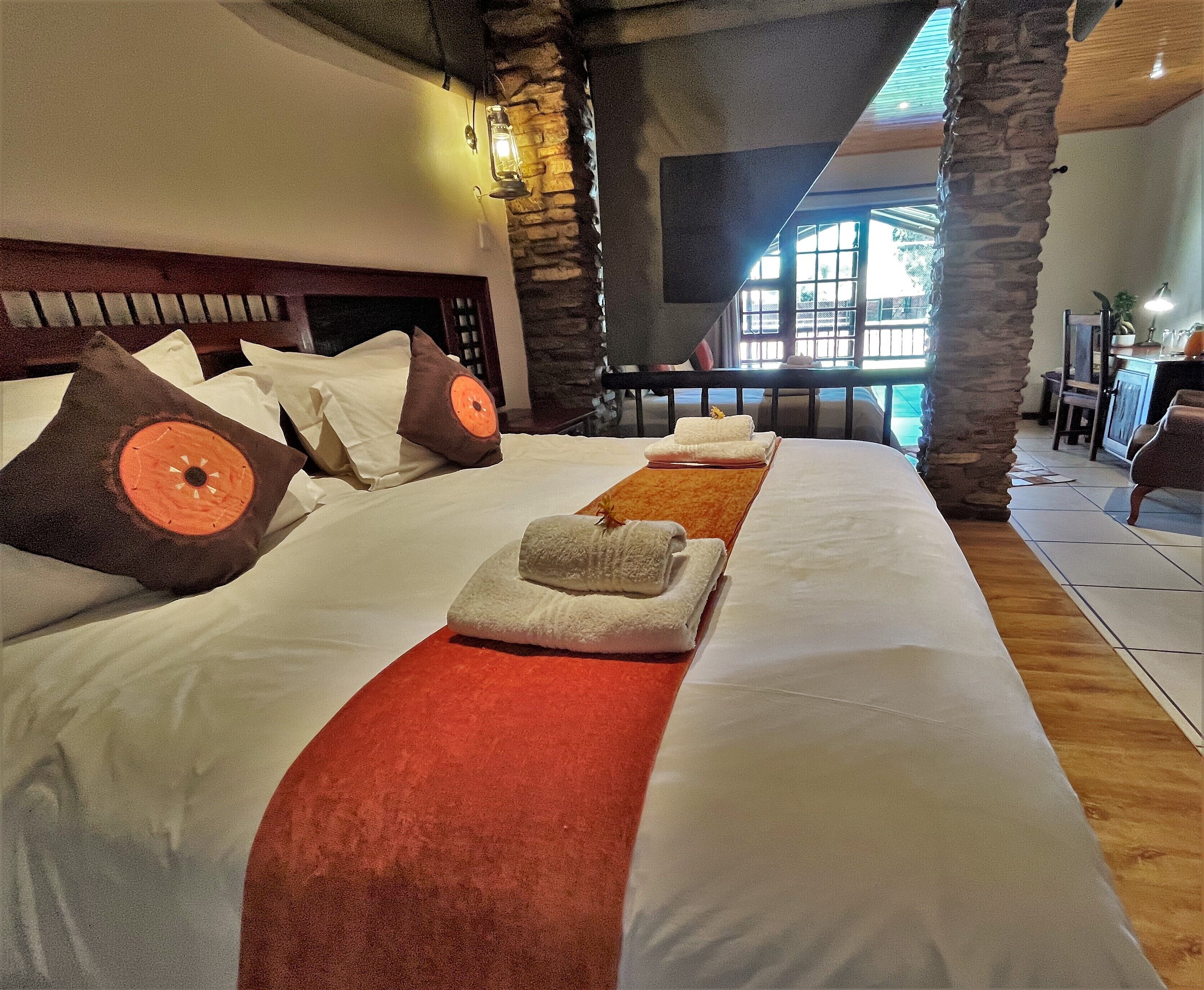 Habitación de hotel con una cama grande, pilares de piedra, chimenea de piedra y vistas al exterior.