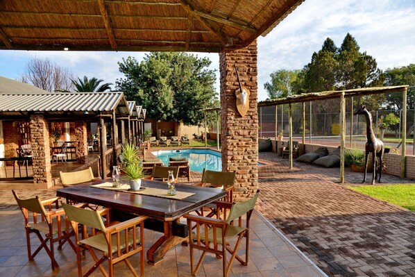 An outdoor patio with a pool, dining area, and giraffe enclosure. - Gamagara Africa private nature reserve (Joe Morolong)