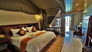 Ein geräumiges Schlafzimmer mit großem Bett, Holz-Kopfstütze und Blick auf den Wohnbereich.