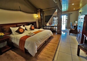 Spaziosa camera da letto con un grande letto, una testata in legno e vista sull'area soggiorno.