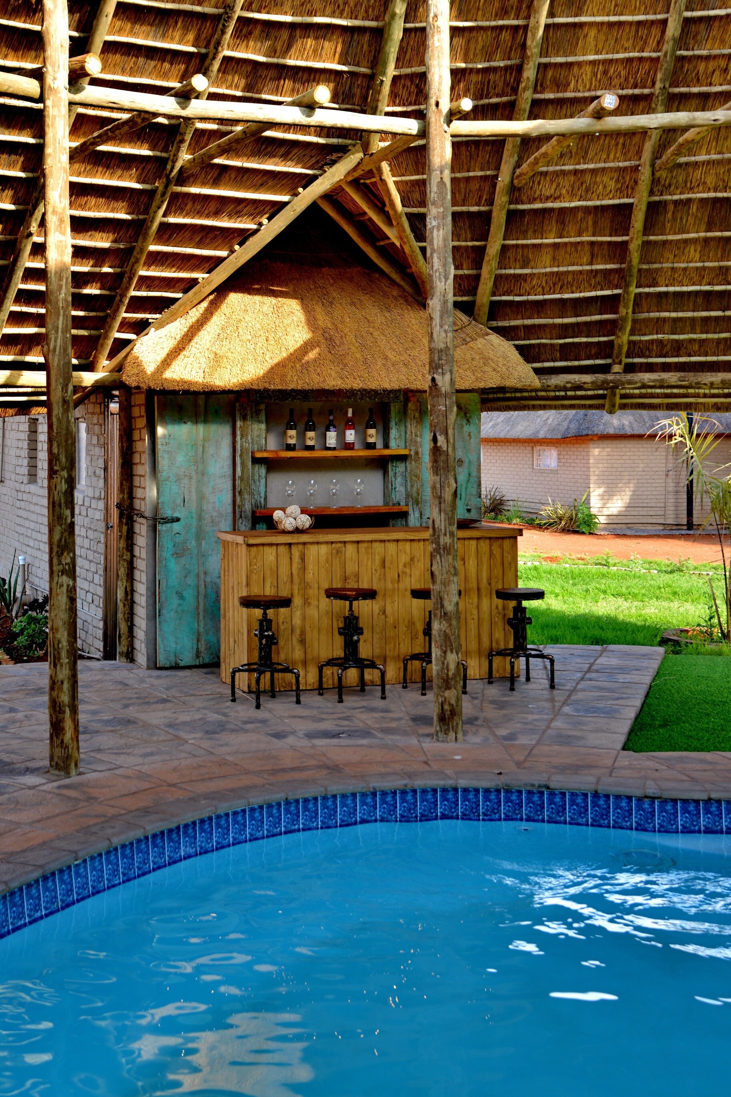 Un bar junto a la piscina con taburetes y techo de paja.