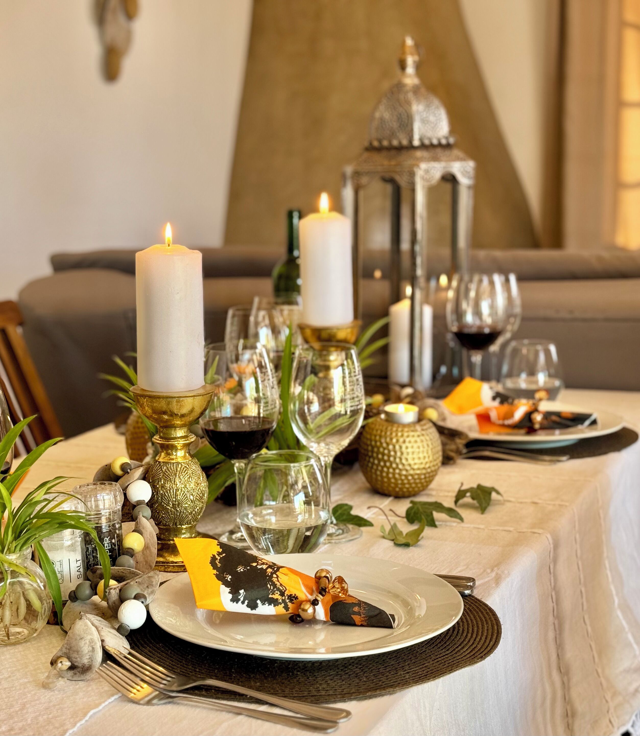 A dining table set with candles, glassware, and decorative elements.