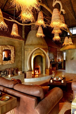 A rustic interior with a fireplace, leather seating, and hanging light fixtures. - Gamagara Africa private nature reserve (Joe Morolong)