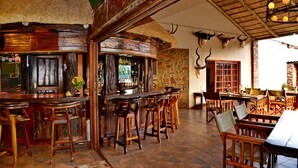 Eine rustikale Bar mit Holzmöbeln und einer Wand aus Stein im Hintergrund.