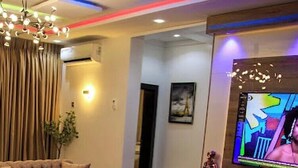 A modern living room with a sofa, armchair, coffee table, and a flat-screen TV mounted on the wall. - The Captains Apartment Abuja (Abuja)