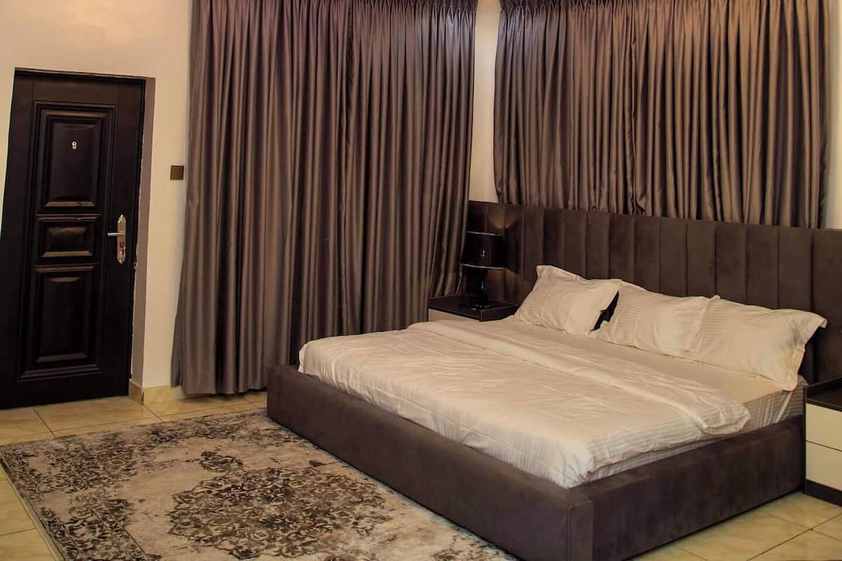 Een slaapkamer met een modern plafond, een groot bed en een nachtkastje.