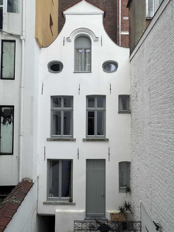 A white building with a grey door and multiple windows.