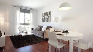 A modern living room with a sofa, a dining table with chairs, a coffee table, and a black rug. - BEAUTIFUL APARTMENT IN EIXAMPLE AREA OF BARCELONA (Barcelona)