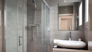 A modern bathroom with a glass-enclosed shower, a white sink, and a mirror above the sink. - BEAUTIFUL APARTMENT IN EIXAMPLE AREA OF BARCELONA (Barcelona)