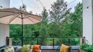 Ein Balkon mit einer Couch, einem Sessel und einem Sonnenschirm.